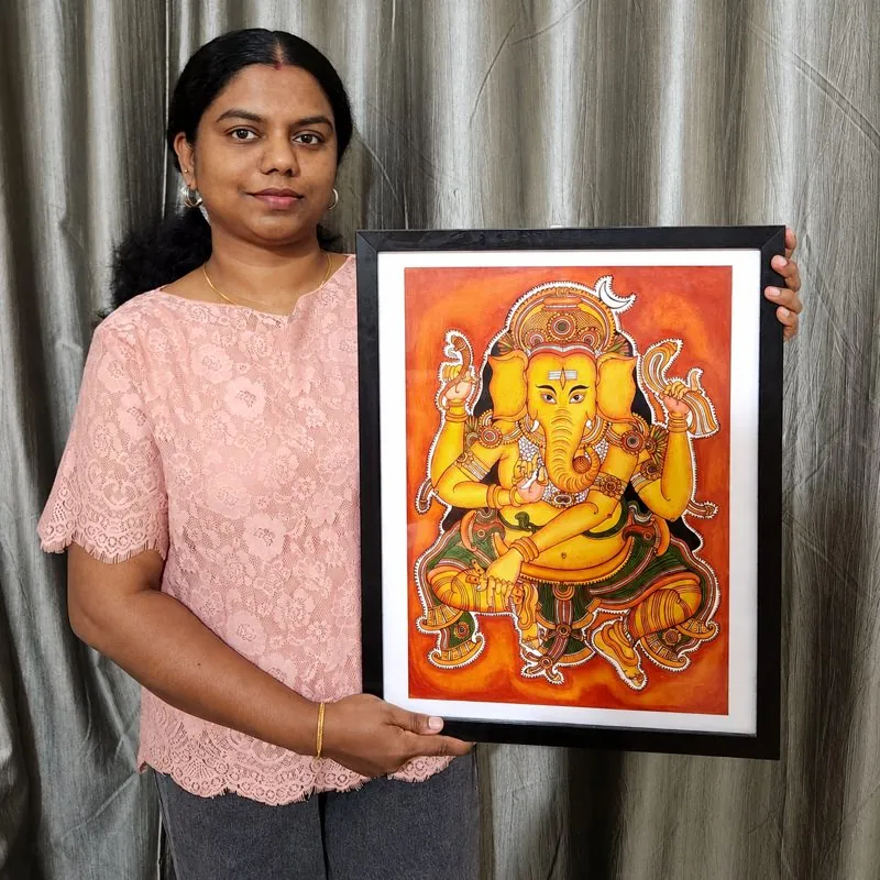 Gopika Vinosh holding her framed Kerala mural Ganesha painting